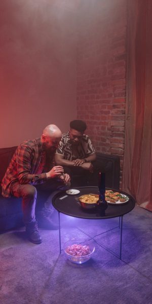 Two Guys sitting on a couch and building a joint, a table with snacks is in frond of them, Happy-CAPTN About us